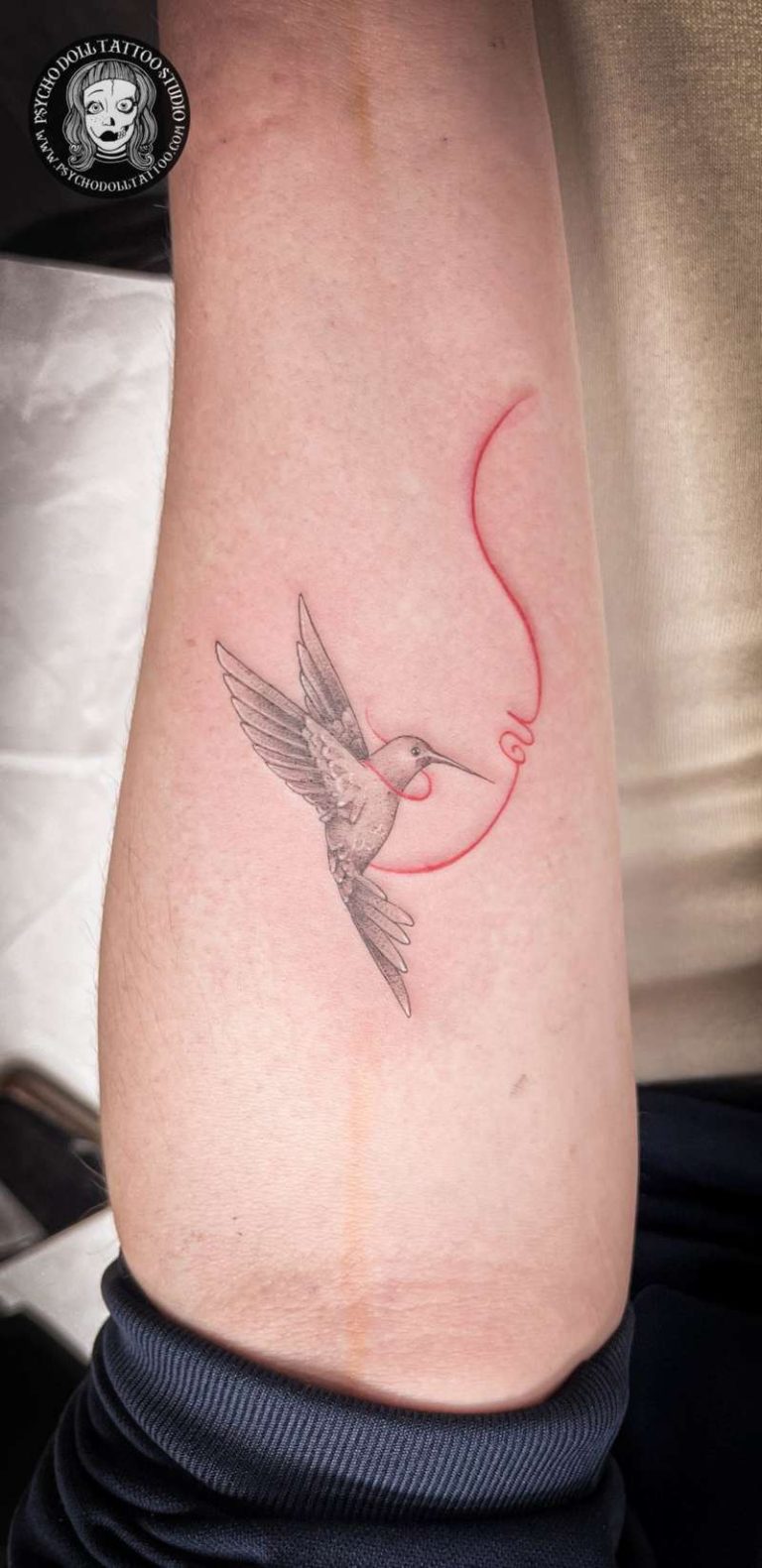 Tatuaje colibrí con inicial e hilo rojo